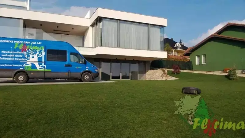 Dodávka spoločnosti Florima parkujúca pred rodinným domom s čerstvo pokosenou trávou, očividne udržiavanou aj za pomoci robota na kosenie trávnika